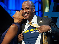Photo: LeShelle May laughs as Chancellor Gary S. May opens his dress shirt to display an Aggie Heroes T-shirt