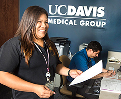 Photo: Office staff Jo Ena Christensen and Hugo Casillas Jimenez, behind counter at the Davis Clinic (UC Davis Medical Group)