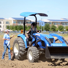 Photo: A TA instructs a student as she learns how to drive a tractor.